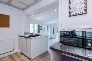 Una cocina moderna con armarios blancos, encimera de granito y microondas integrado.