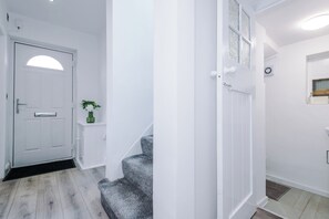 Ein Flur mit einer weißen Tür, einer kleinen Pflanze und einer Treppe.