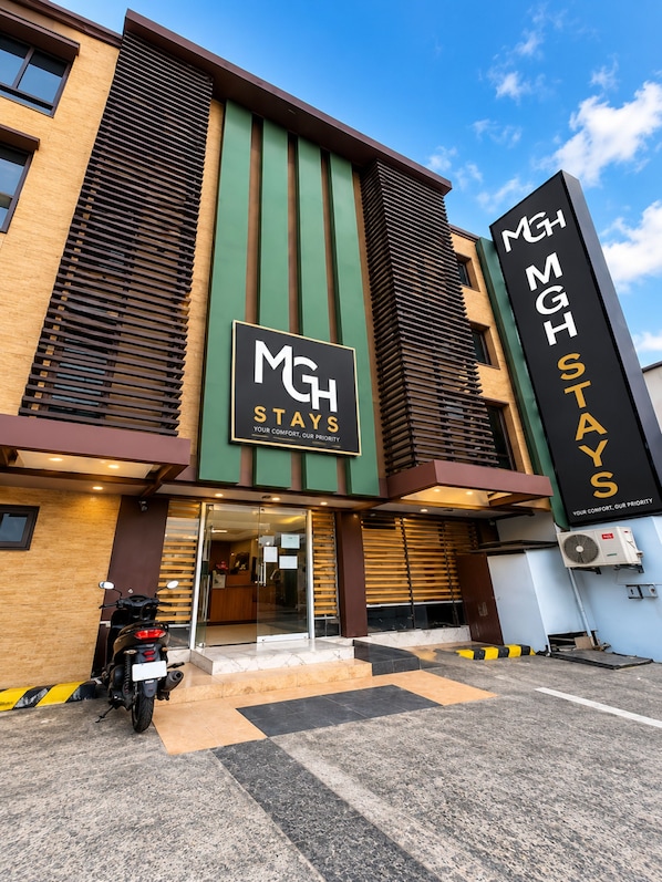 A hotel entrance with a sign reading 'MGH STAYS YOUR COMFORT OUR PRIORITY'. - MGH Stays Quezon City (Quezon City)