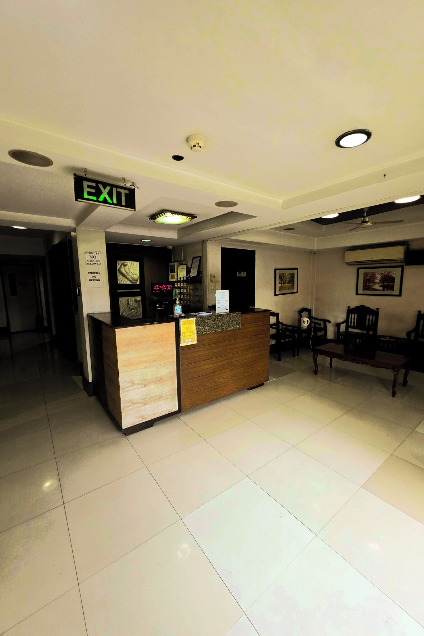 Zona de recepción de un hotel, con un mostrador, un reloj y una señal de salida.