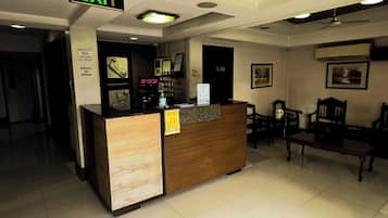 Zona de recepción de un hotel, con un mostrador, un reloj y una señal de salida.