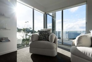 A modern living room with a large window, a beige sofa, and a small table with books.