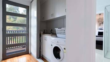 Une buanderie équipée d’un lave-linge, d’un sèche-linge et d’un panier à linge.