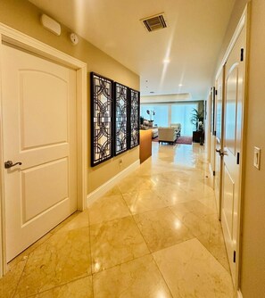 A hallway with a marble floor, white doors, and a decorative wall panel. - Wake Up by the Sea - Paradise in Cozumel (Cozumel)