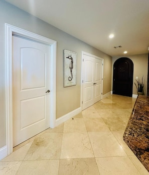 A hallway with white doors, a framed seahorse artwork, and a dark archway at the end. - Wake Up by the Sea - Paradise in Cozumel (Cozumel)