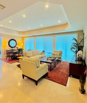 A spacious living room with a high ceiling, large windows, and a dining area with a round table and chairs. - Wake Up by the Sea - Paradise in Cozumel (Cozumel)