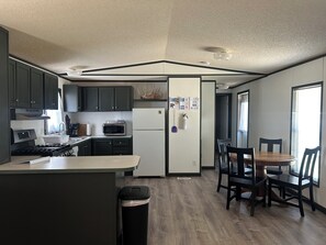 A compact kitchen with a central island, a dining area with a wooden table and chairs, and a view of the adjacent room.