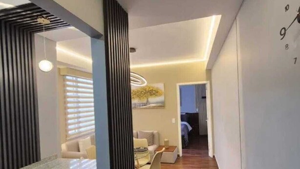 Una cocina moderna con una isla integrada, una zona de comedor con una mesa redonda y una sala de estar con sofá y un cuadro.
