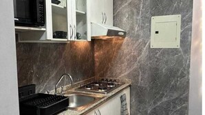 Cocina compacta con estufa a gas, microondas y lavamanos.