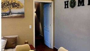 Un interior moderno con una zona de comedor que incluye una mesa y sillas de vidrio, un sofá y un cuadro de un árbol.
