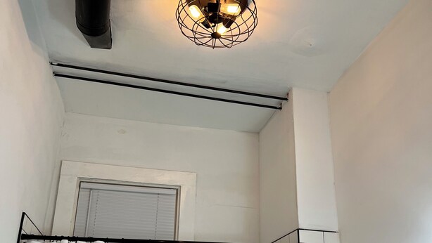 A bathroom with white tiled walls, a shower enclosure, a white curtain, and a ceiling light fixture. - Historic Apt. Adjacent to Capitol/2 Queen Bds Loft Style near Medical/State Fair (Springfield)