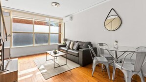 Un salon moderne avec un canapé, une table basse en verre et une table à manger avec des chaises.