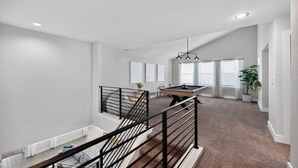 A spacious living area with a pool table, a staircase, and a view of the backyard. - Modern 4BR, Sleeps 10, King Suite, Home Office, Garage Gym & Game Room (Manor)