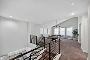 Ein geräumiges Wohnzimmer mit Billardtisch, einer Treppe und Blick auf den Garten.
