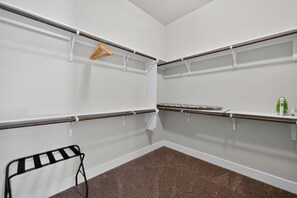 Ein Zimmer mit weißen Wänden, braunem Teppich und Regalen mit Kleiderhaken.