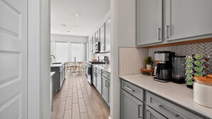A modern kitchen with grey cabinets, a herringbone backsplash, and a coffee machine. - Modern 4BR, Sleeps 10, King Suite, Home Office, Garage Gym & Game Room (Manor)