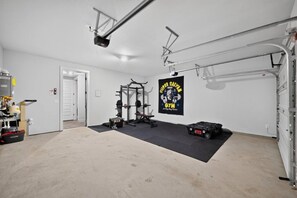 Eine Garage mit einem Bereich zum Gewichtheben, einer Tür, die in einen anderen Raum führt, und einem an der Wand befestigten Poster.