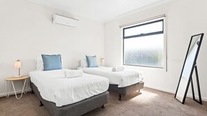 Una camera d'albergo con due letti, uno specchio a figura intera e un'ampia finestra.