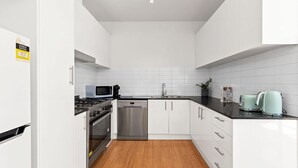Una cucina moderna con pensili bianchi, una lavastoviglie in acciaio inossidabile, un forno a microonde, un piano cottura e un lavello.