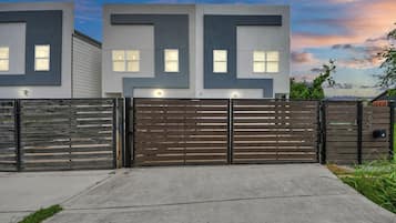 Een modern, twee verdiepingen tellend huis met een hekwerk en een betonnen pad naar de ingang.