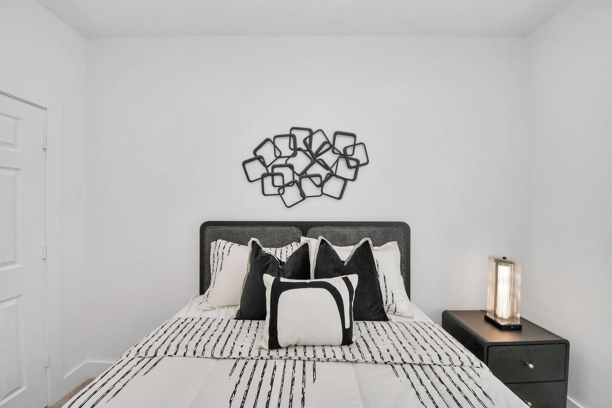 Une chambre à coucher avec un lit, des oreillers, une table de chevet et un élément décoratif mural.