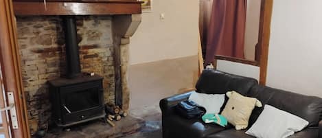 A living room with a fireplace, a leather sofa, and a brick wall.