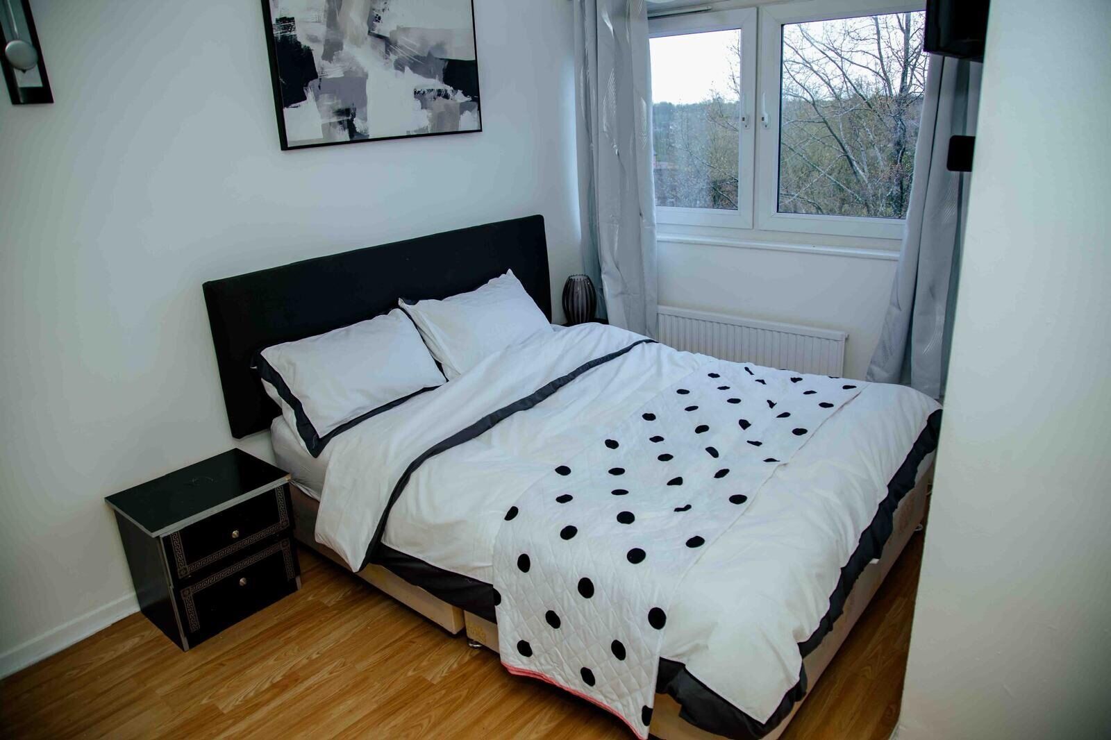 A bedroom with a bed, bedside table, and a window.