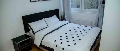 A bedroom with a bed, bedside table, and a window.
