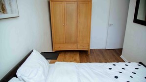 A bedroom with a bed, a wooden wardrobe, and a door. - Manchester City Short Let (Manchester)