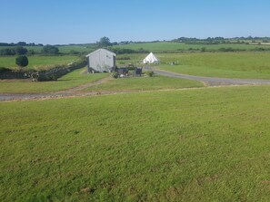 Un paysage rural avec une grange, une tente blanche et un mur de pierres.