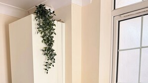 A kitchen with white cabinets, a stainless steel sink, a microwave, and a plant on the wall. - Apartment Sleeps 6 with in Kilburn Lane (London)