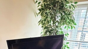 A black entertainment unit with a flat-screen TV, a clock, and a small speaker. - Apartment Sleeps 6 with in Kilburn Lane (London)