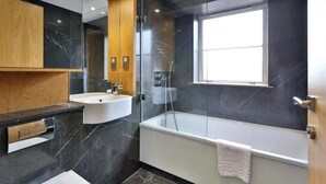 Ein modernes Badezimmer mit Badewanne, Waschbecken, Spiegel und Fenster.