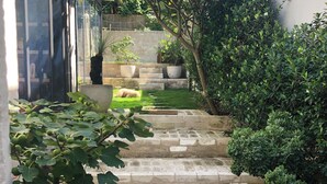 A stone staircase leading to a grassy area with potted plants and a small animal enclosure. - Bronte garden apartment (Waverley)