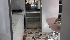 A modern kitchen with a marble countertop, a gas stove, and a patterned floor. - Bronte garden apartment (Waverley)