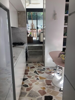 A modern kitchen with a marble countertop, a gas stove, and a patterned floor. - Bronte garden apartment (Waverley)