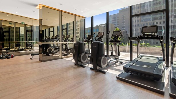 Uma academia moderna com equipamentos de cardio, máquinas de peso e um espelho grande.