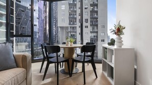 Um apartamento moderno com área de jantar, janelas amplas e vista para edifícios altos.