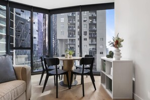 Eine moderne Wohnung mit Essbereich, großen Fenstern und Blick auf hohe Gebäude.