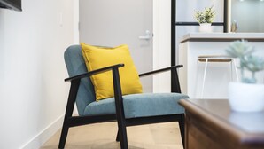A chair with a yellow cushion in a room with a wooden floor and a white wall.