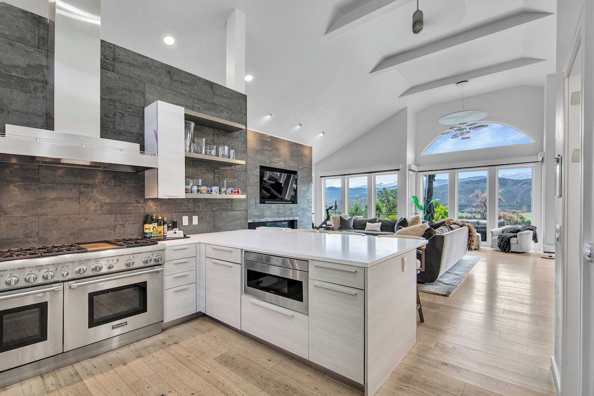 A modern kitchen with a large island, built-in appliances, and a view of the outdoors.