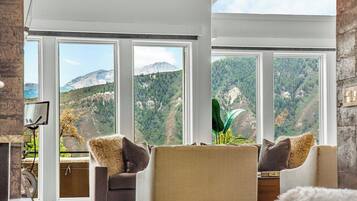 A living room with large windows, a fireplace, and a view of a mountainous landscape.
