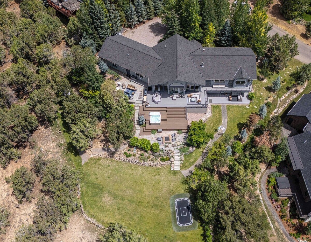 A large house with a spacious deck, a hot tub, and a well-maintained lawn.
