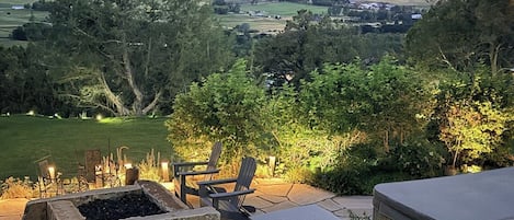 An outdoor deck with a hot tub, seating area, and a fire pit.
