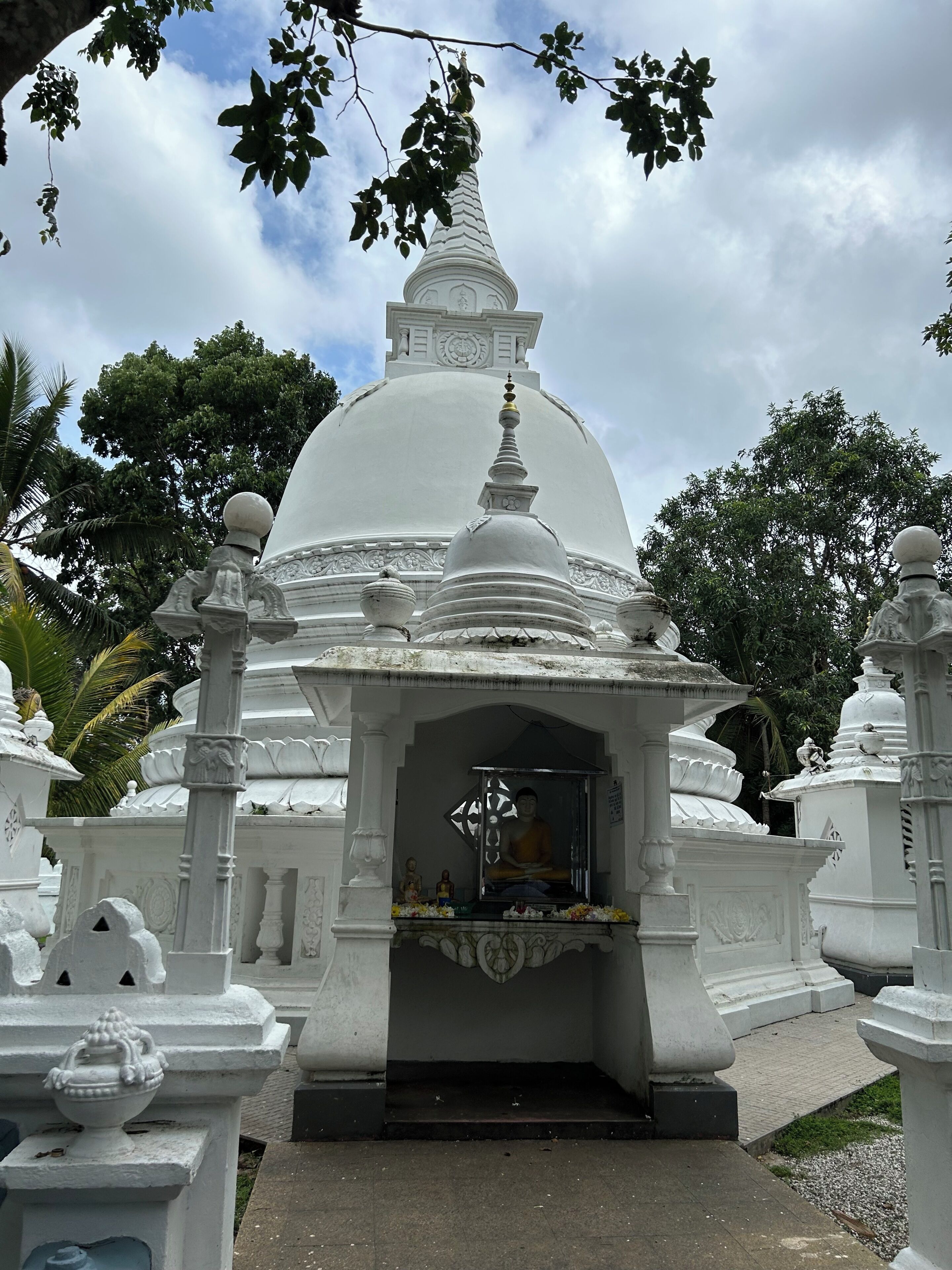 A white temple structure with a central dome and a seated figure inside.