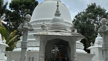A white temple structure with a central dome and a seated figure inside.