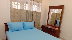 A bedroom with a bed, a dresser, a mirror, and curtains. - Serenity Nest Holiday Home, Bollatha Ja Ela, Sri Lanka (Bollate)