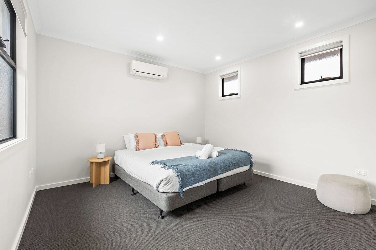 A bedroom with a bed, bedside table, lamp, and a small window.