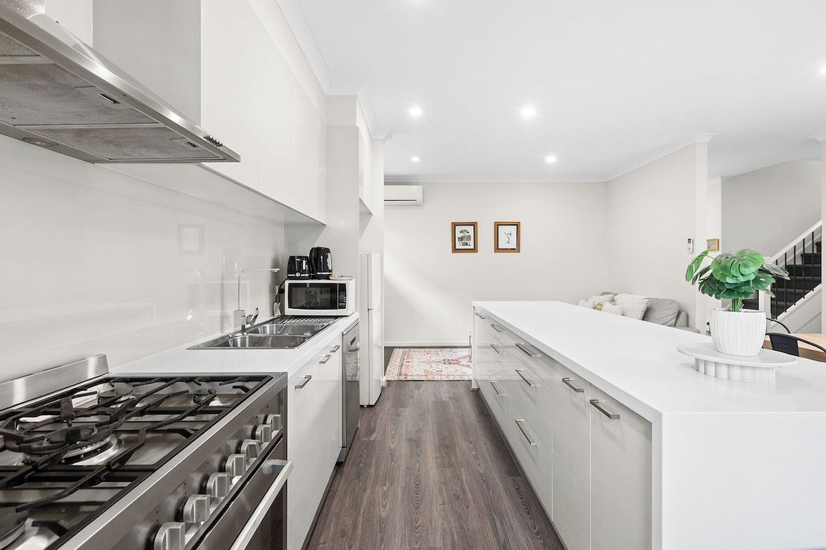 A modern kitchen with a gas stove, microwave, and white cabinetry.