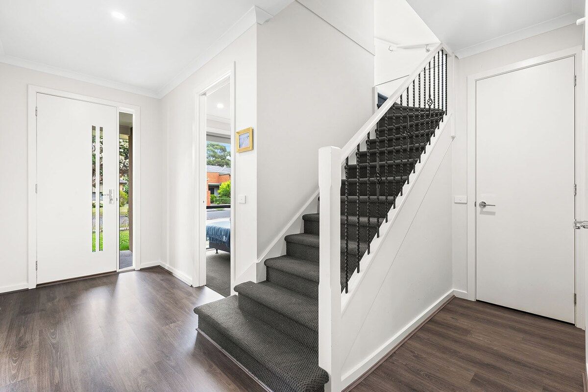 A staircase with dark carpeted steps and white handrails, leading to a door.